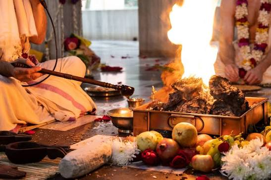 Sacred fire offering with hands placing offerings into the yajna kunda